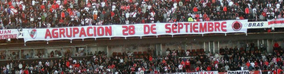 La bandera de la Agrupación 28 de Septiembre colgada en la tribuna del Monumental, con la hinchada detrás